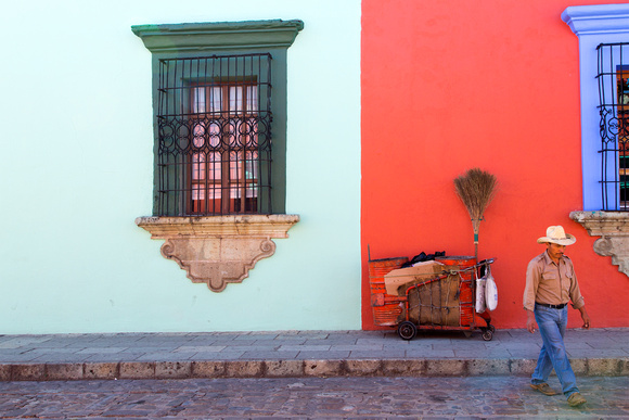 Street cleaner walking in front of colorful wall